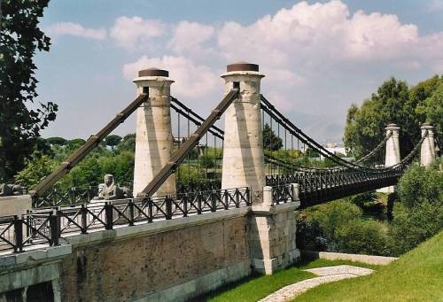 The Real Ferdinando chain suspension bridge over the Garigliano, with its stone towers and iron chains, under a summer sky