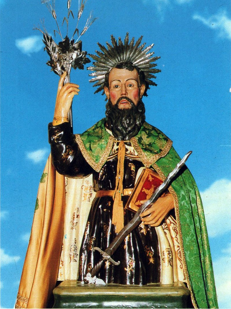 Painted statue of Saint Elia the Prophet with a halo, holding a sword and a book, in a green and gold cape
